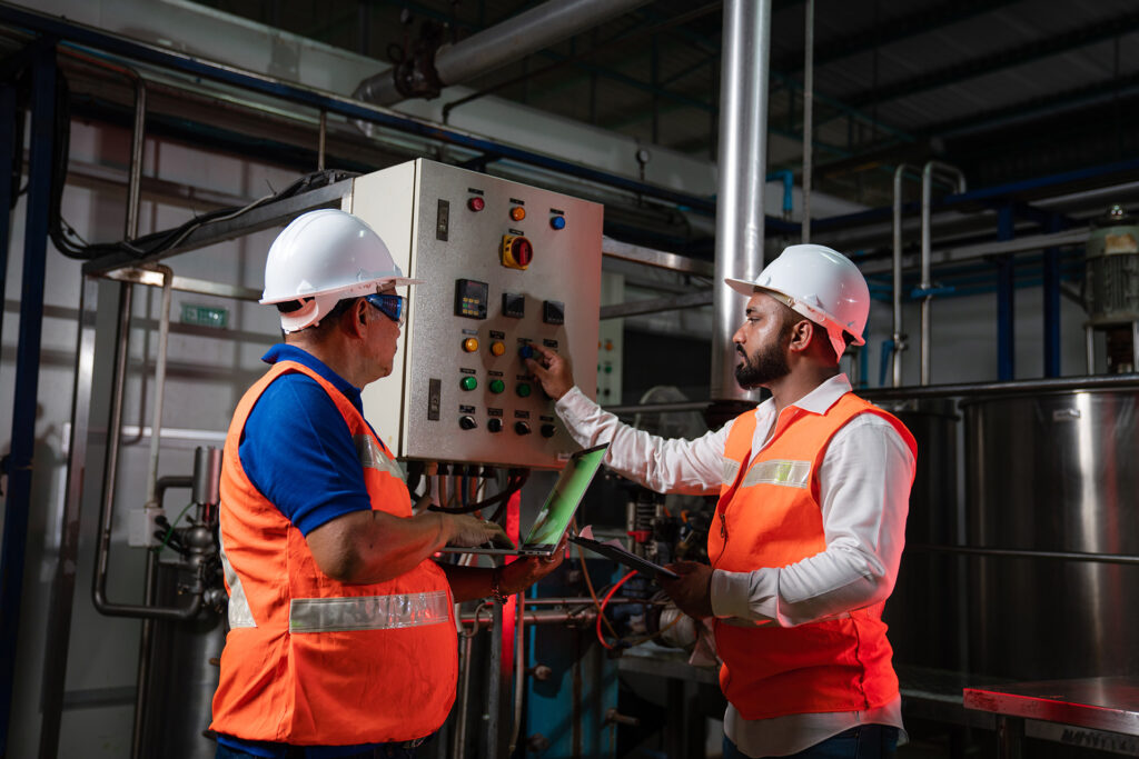 Two Engineers Infront of Commercial Machinery Discussing Planned Maintenance Needs